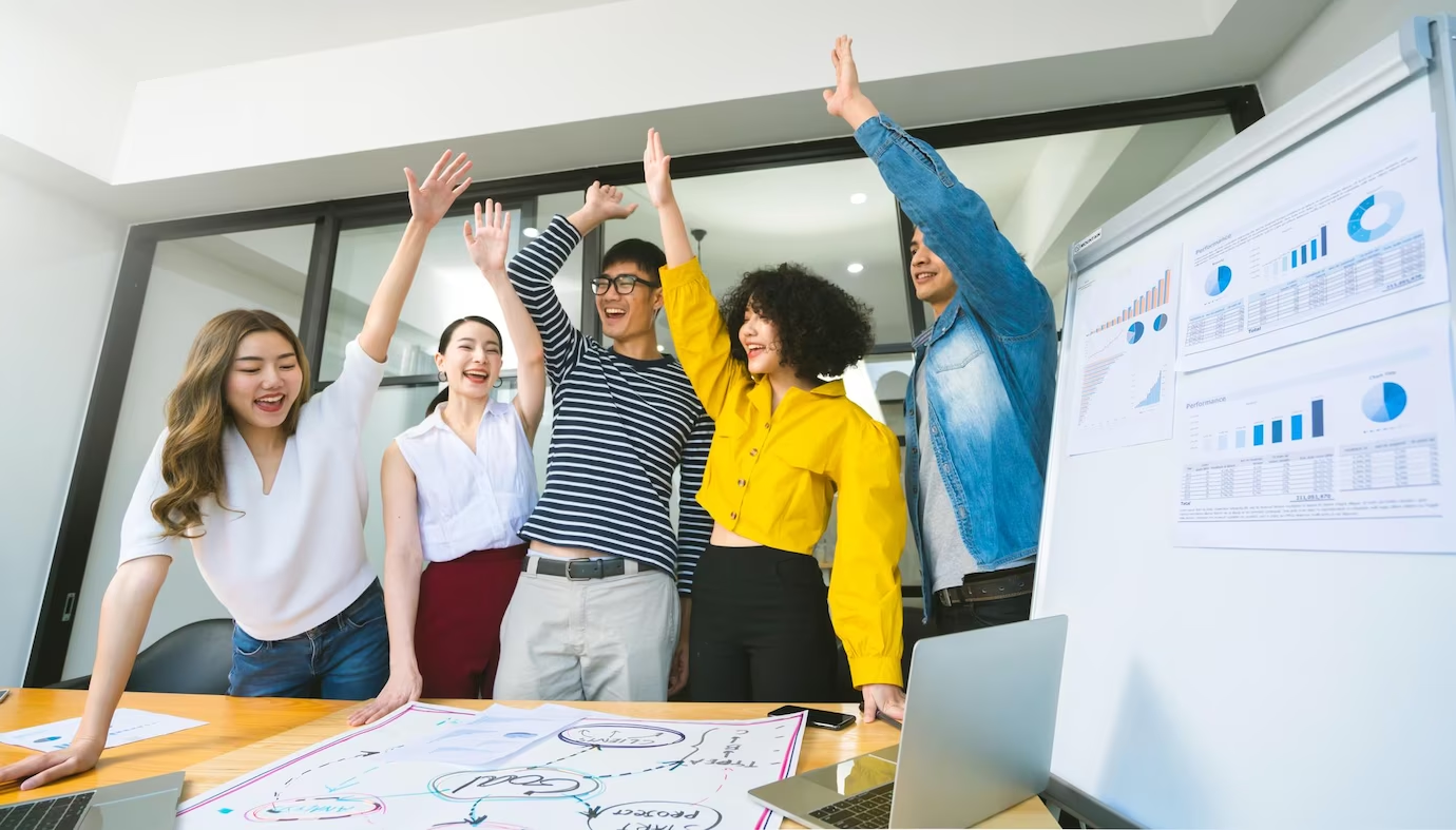 People celebrating in an office, raising their hands