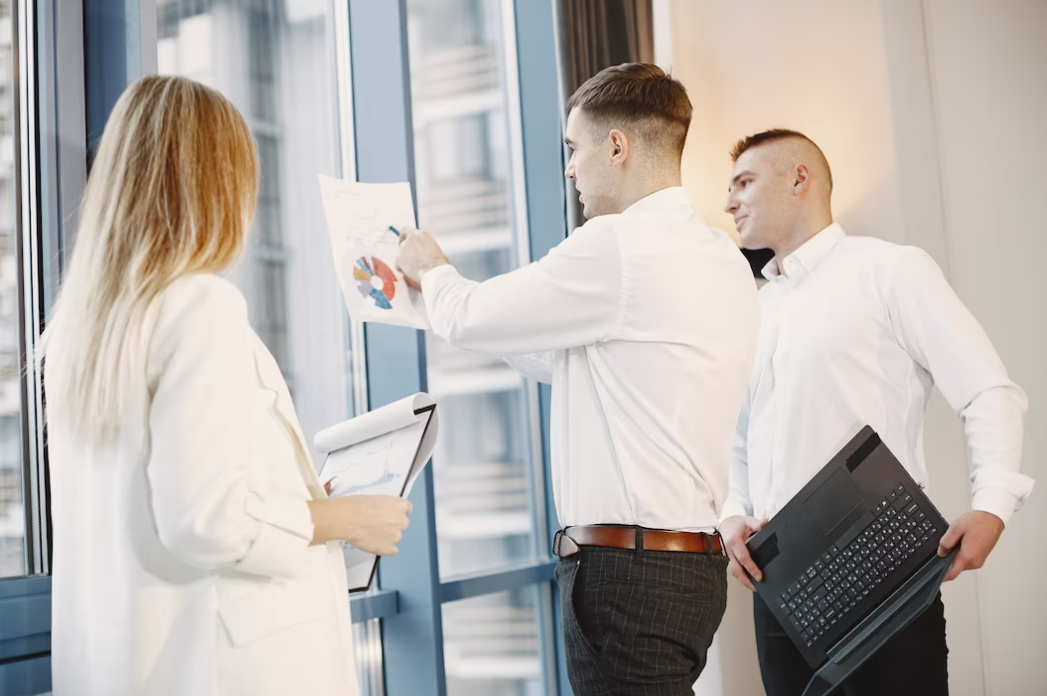 people in the office creating a new project, one shows a graph on the paper